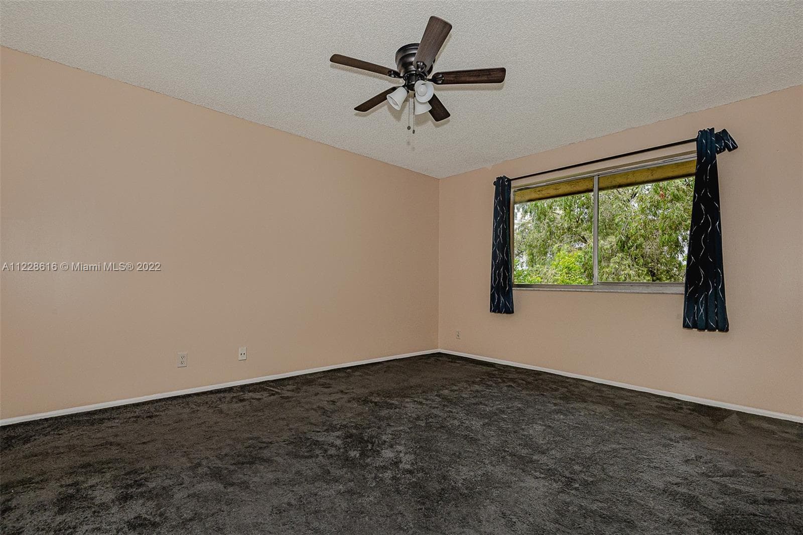 The master bedroom with a large window and a view of the water and trees outside.