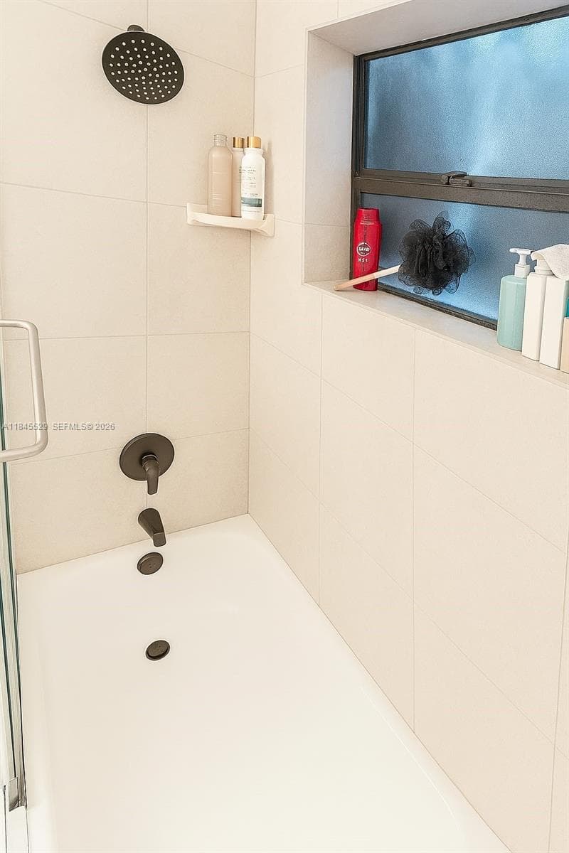 Beautifully tiled shower space with bathtub & privacy window niche, shelving, and natural light