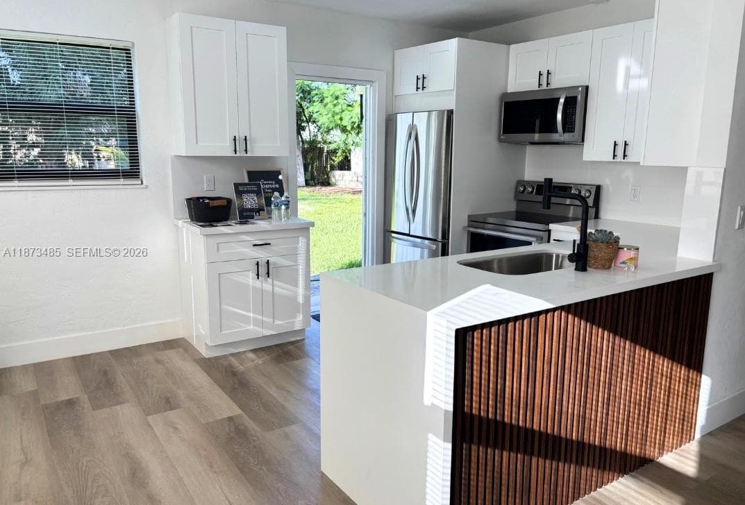 Fully renovated kitchen boasting sleek quartz countertops, stainless steel appliances.