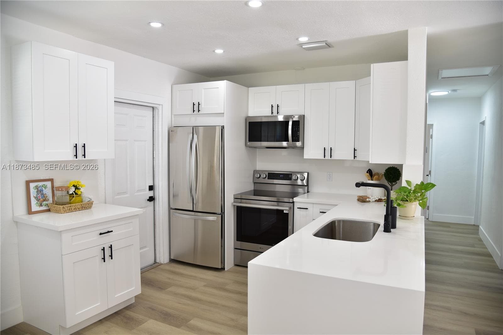 Bright and airy living space featuring new wood-look tile flooring and modern light fixtures, creating a welcoming atmosphere.