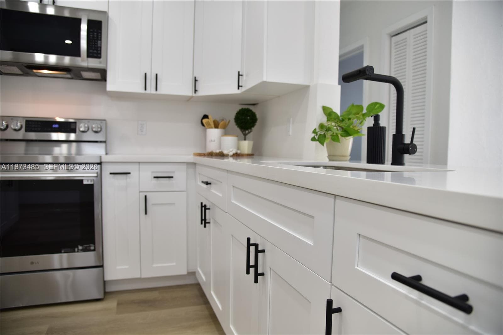 Fully renovated kitchen boasting sleek quartz countertops, stainless steel appliances.