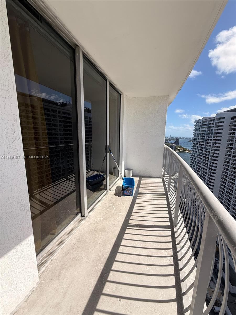 Covered outdoor balcony featuring full-height glass sliding doors and a metal railing