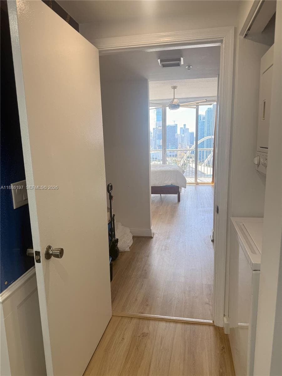 Built-in laundry closet, wood-finish flooring, floor-to-ceiling windows, and ceiling fan fixture