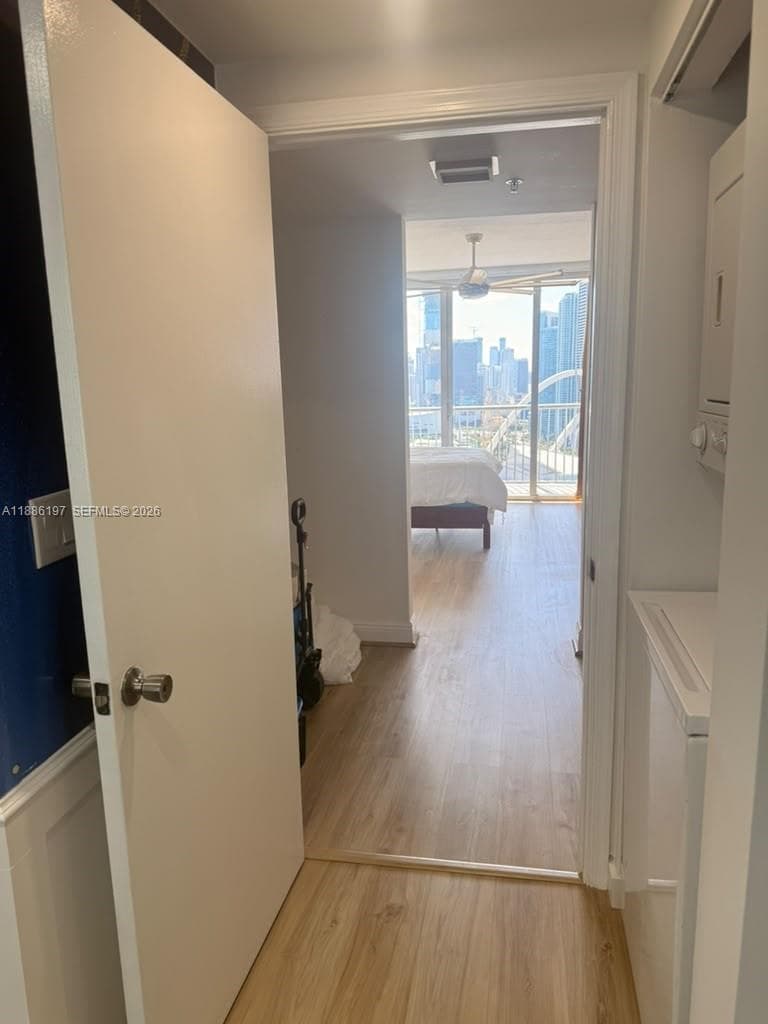 Entryway featuring wood-finish flooring, white door casing, and integrated laundry area with stacking units