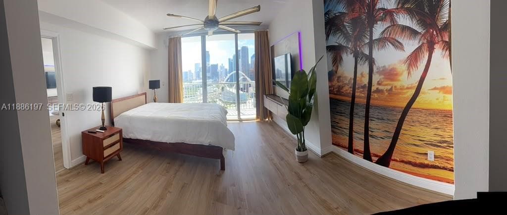 Wood-finish flooring, floor-to-ceiling glass panel windows, integrated wall-mounted media cabinetry, and a ceiling fan with multi-blade design
