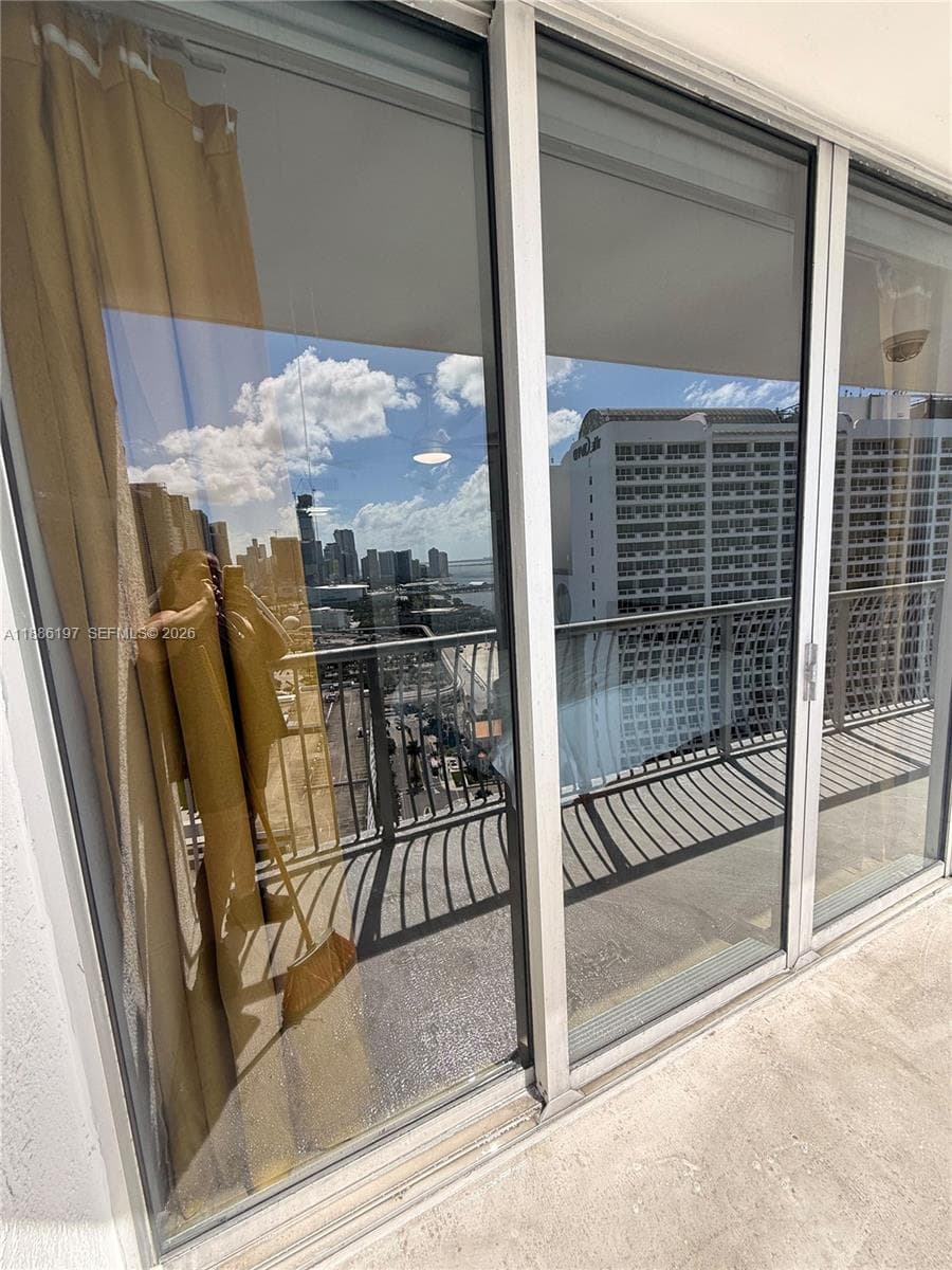 Floor-to-ceiling sliding glass doors with aluminum framing opening to a private balcony featuring metal railings and concrete flooring