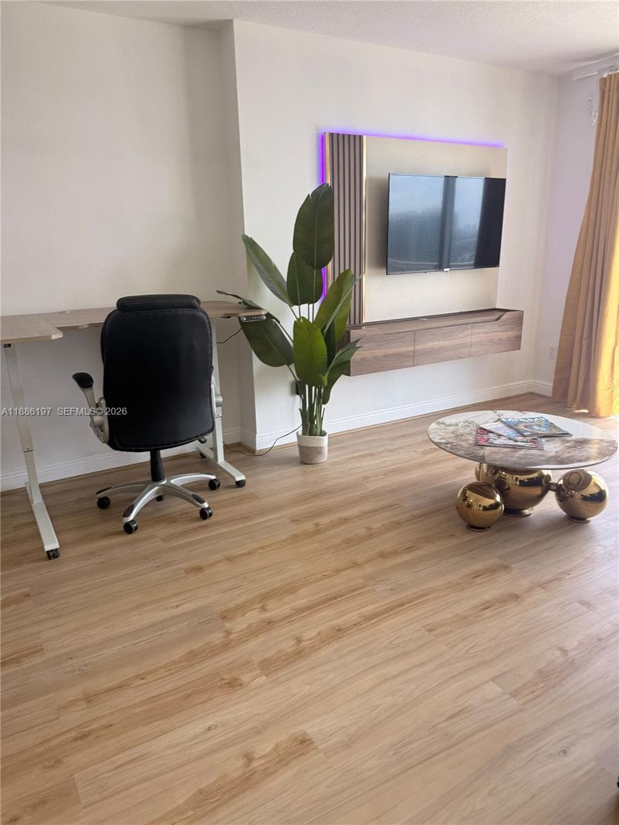 Wood-finish flooring and a built-in wall-mounted entertainment console featuring vertical accent paneling and integrated lighting