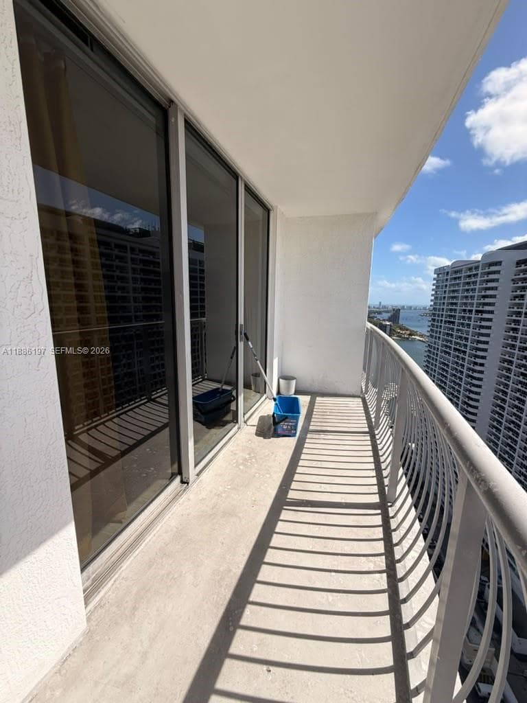 Private balcony featuring concrete flooring, a curved metal railing, and floor-to-ceiling sliding glass doors