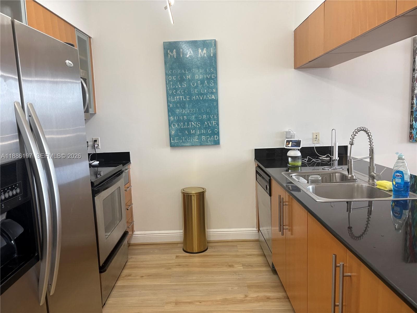 Kitchen featuring flat-panel wood cabinetry, dark stone countertops, stainless steel appliances, and wood-finish flooring