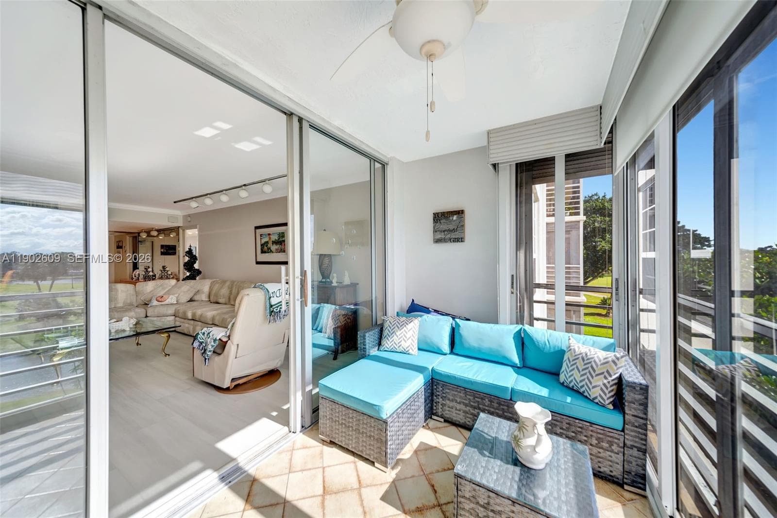 Bright, comfortable bedroom with neutral walls, custom shutters, and soft carpeting. A ceiling fan and generous wall-to-wall windows create a calm, breezy retreat with plenty of natural light