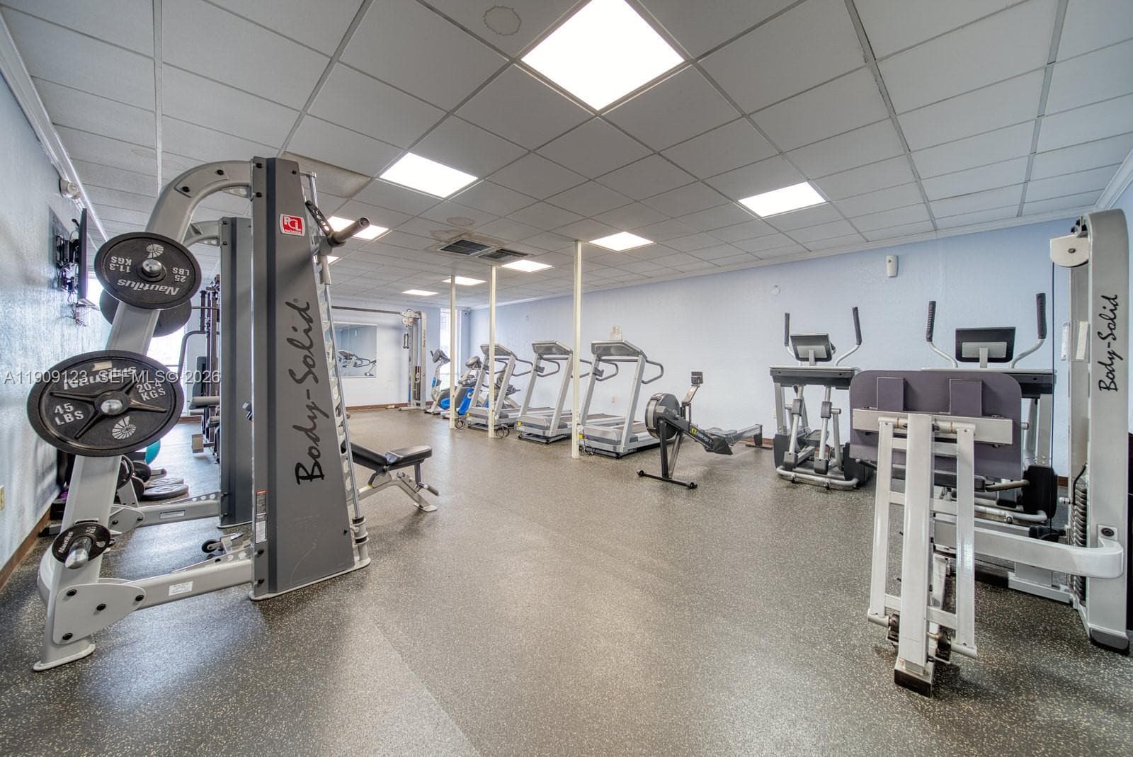 Bright fitness area with large mirrors and equipment variety.