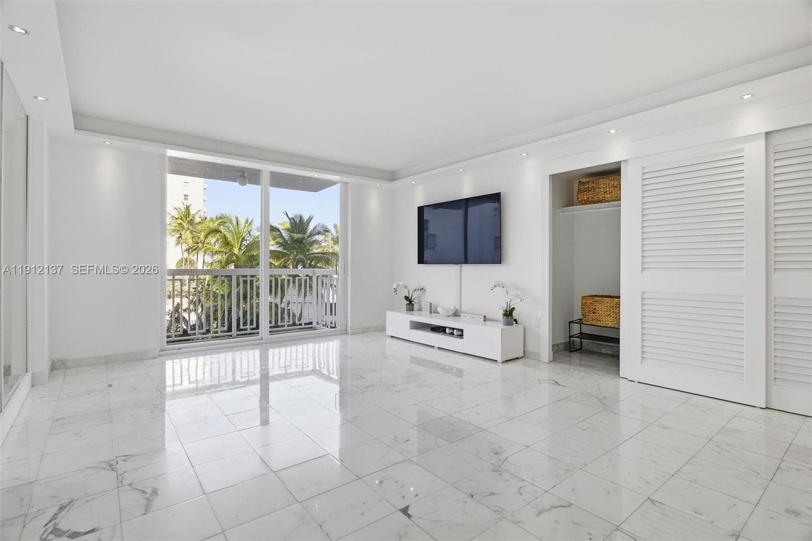 Step into this bright and elegant oceanfront studio, where modern design meets coastal serenity. Gleaming floors, floor-to-ceiling mirrors, and expansive sliding glass doors fill the space with natural light and offer lush views of palm trees and the ocean beyond. The open layout provides a perfect canvas for a luxurious living and sleeping area, while refined finishes and recessed lighting create a sophisticated ambiance
