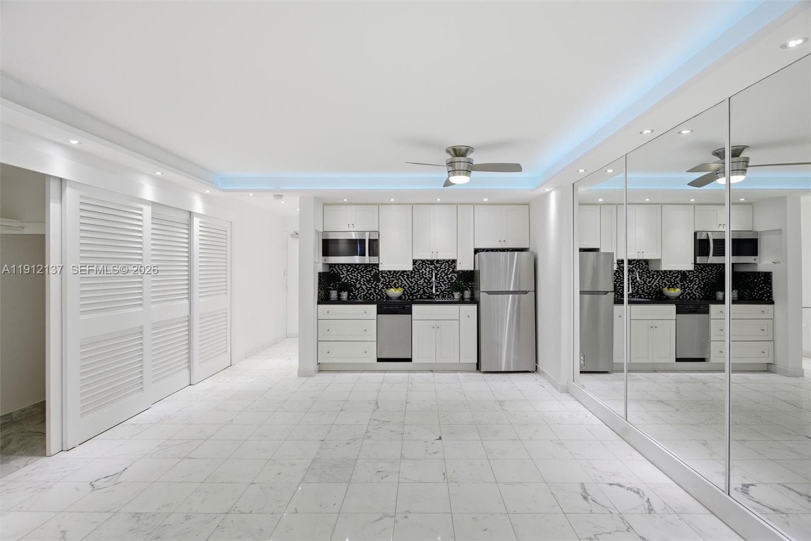 Gleaming floors, mirrored walls, and soft recessed lighting create an airy, sophisticated ambiance. The ceiling features ambient LED lighting that adds a touch of luxury and highlights the studio’s sleek, minimalist design. Expansive sliding glass doors flood the space with natural light with remote control blackout curtains