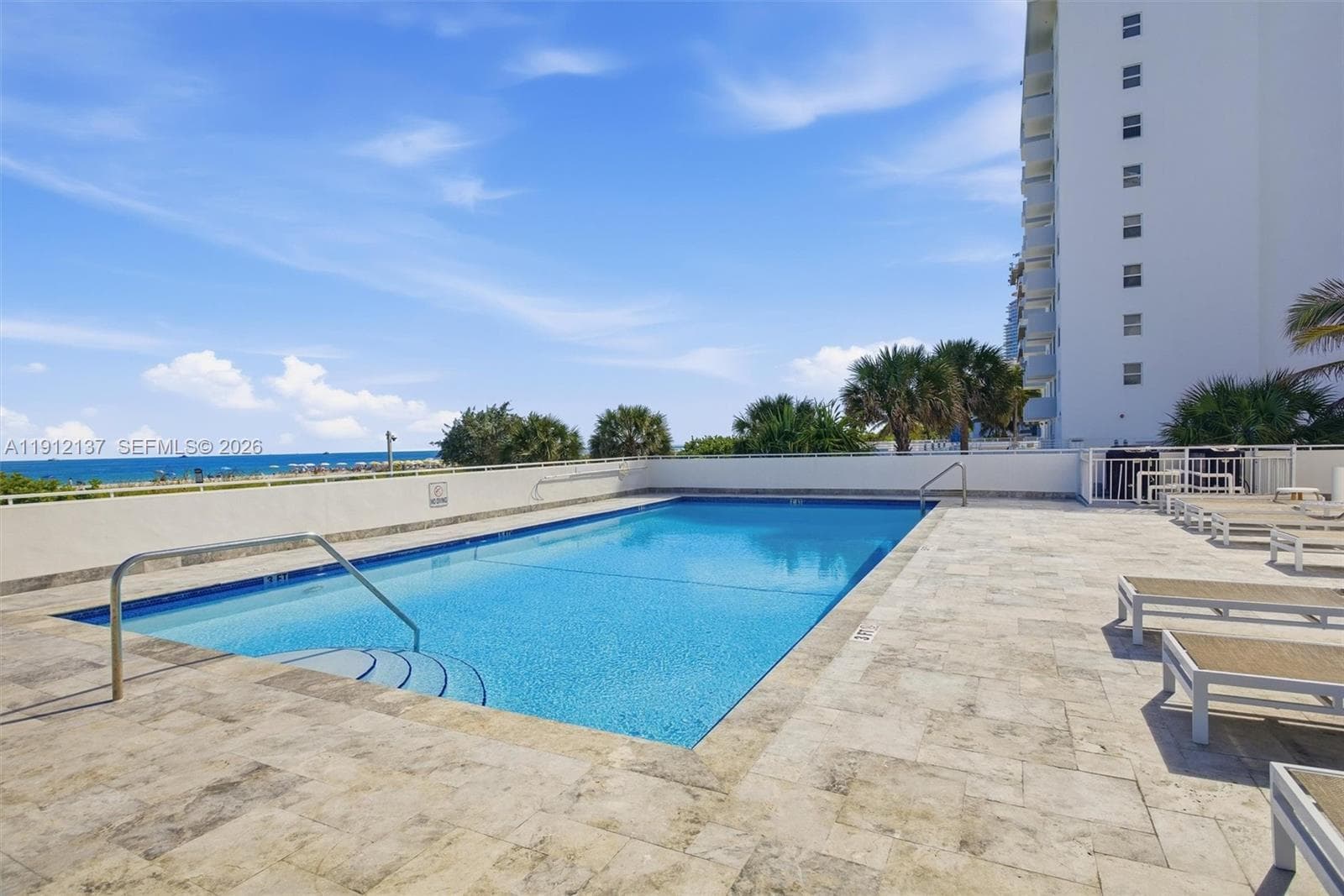Enjoy the ultimate Miami Beach lifestyle at this oceanfront pool deck, where every swim comes with panoramic views of the Atlantic. Surrounded by tropical palms and bathed in sunshine, the sparkling pool offers a serene retreat just steps from the sand. Lounge in style on the expansive sundeck, unwind under the clear blue sky, or take in the breathtaking ocean vistas that stretch endlessly to the horizon.