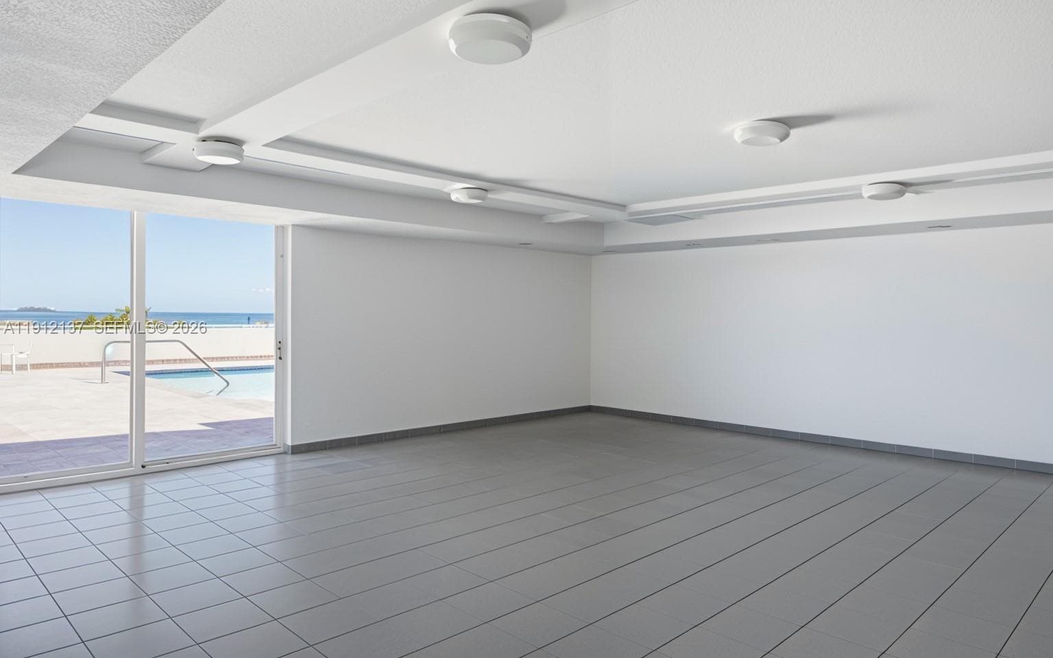 This bright and versatile recreational room offers the perfect space for gatherings, fitness, or relaxation. Framed by floor-to-ceiling windows that open to the oceanfront pool deck, the room is filled with natural light and coastal views. Its open layout and modern design provide endless possibilities — from hosting social events to creating a serene yoga or wellness space. With direct access to the pool and breathtaking ocean backdrop, this amenity embodies the effortless indoor-outdoor lifestyle