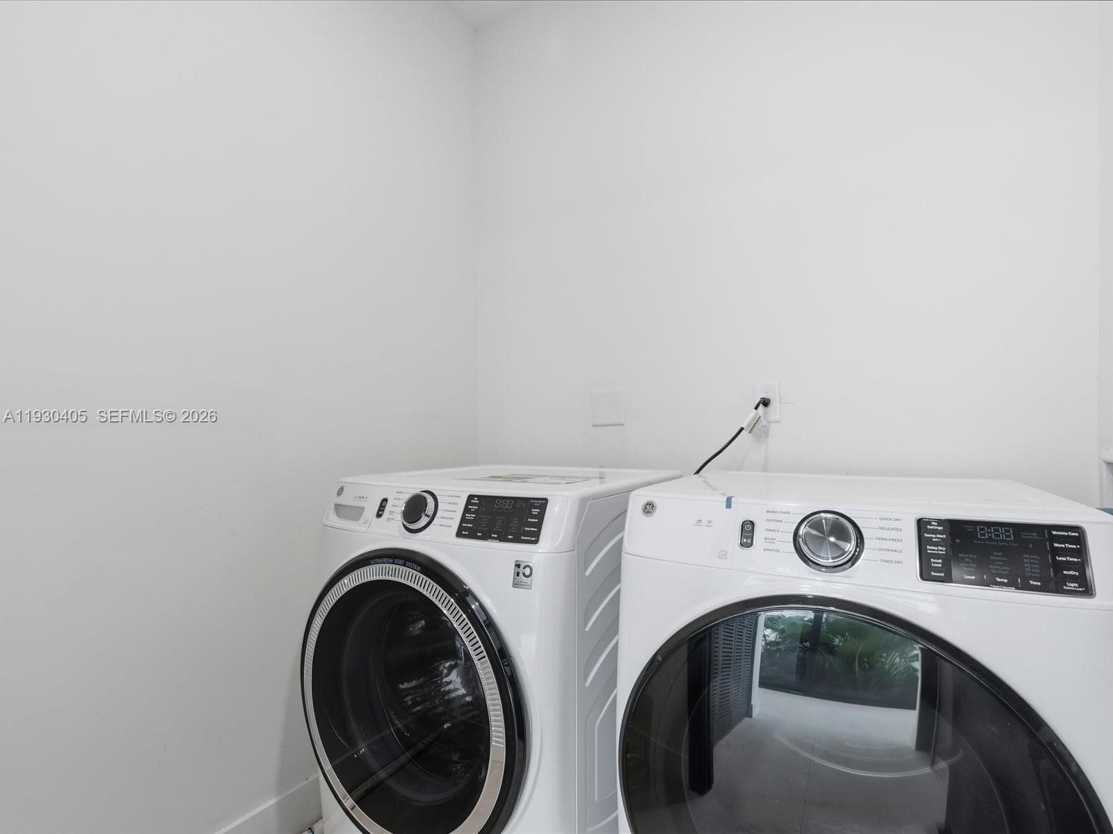 Dedicated laundry area featuring white front-loading high-efficiency appliances with glass-front doors and digital interface controls