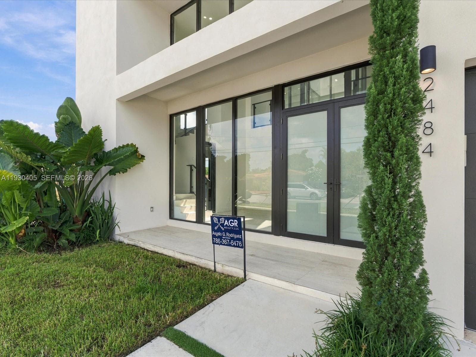 Modern facade featuring smooth stucco finish, floor-to-ceiling glass paneling, double-entry doors, recessed lighting, and concrete entryway