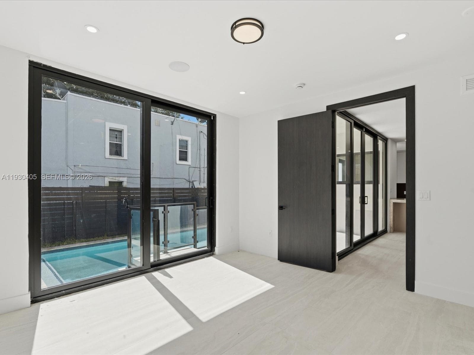 Floor-to-ceiling black-framed sliding glass doors, recessed lighting, wood-finish flooring, and solid-core dark wood interior doors