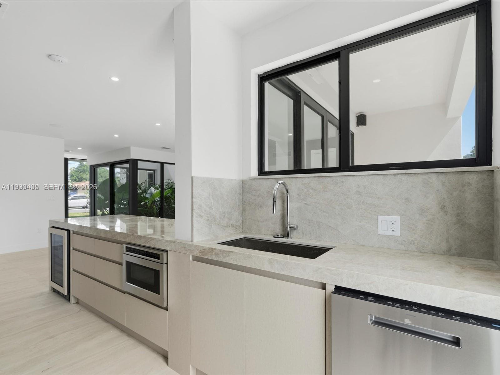 Kitchen featuring stone countertops, integrated stainless steel appliances, a built-in wine refrigerator, flat-panel cabinetry, and black-framed windows