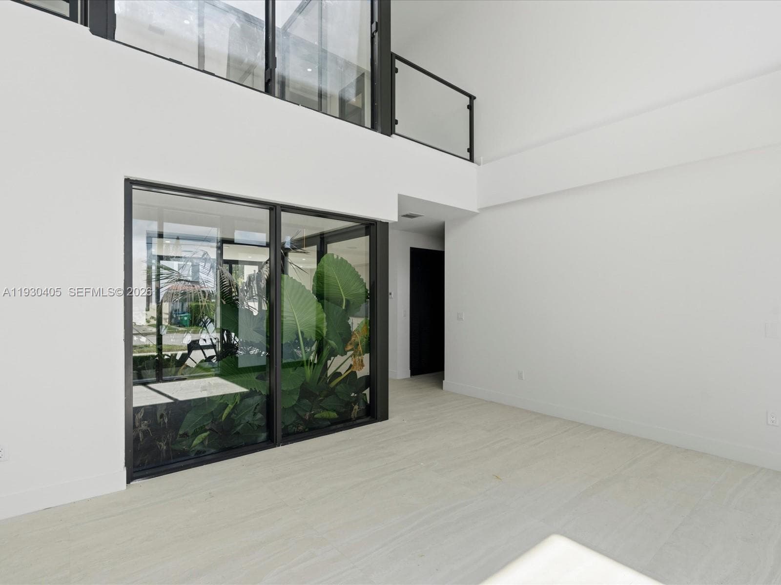 Double-height ceilings, floor-to-ceiling glass wall panels, large-format tile flooring, and a glass-paneled staircase railing