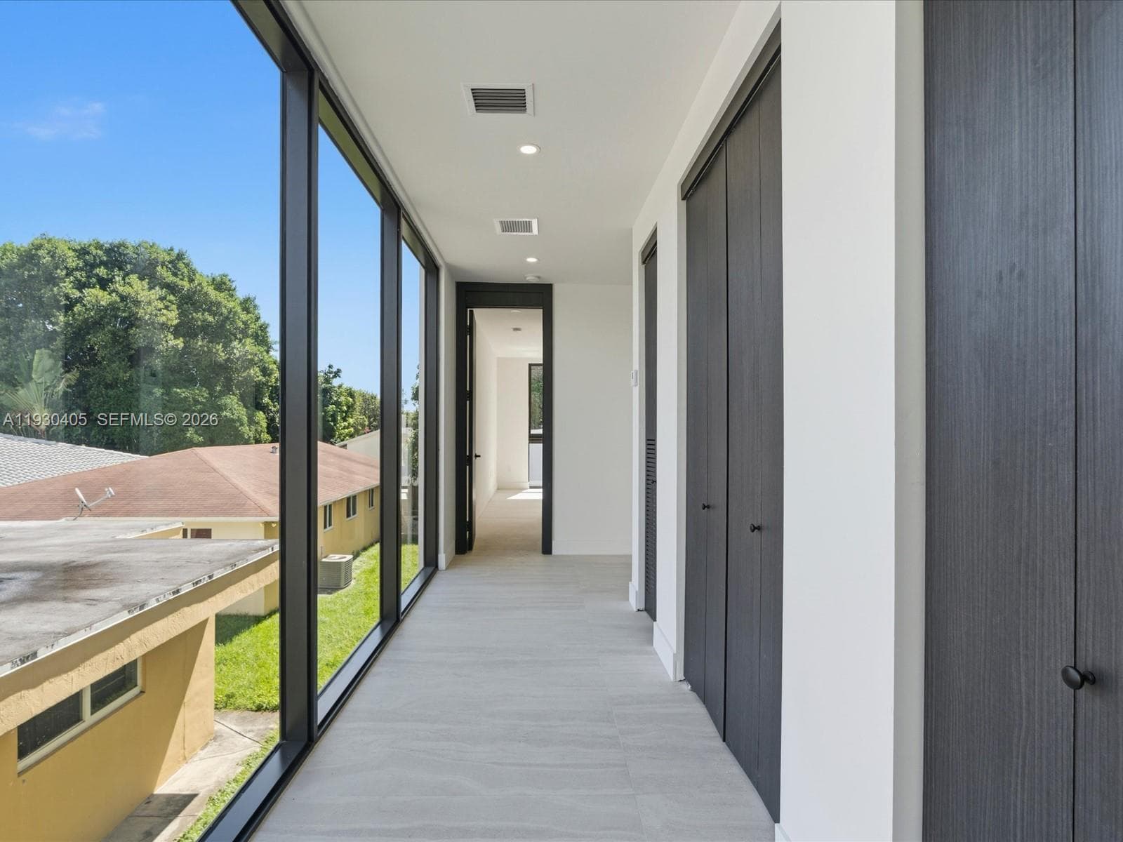 Floor-to-ceiling windows, neutral tile flooring, recessed lighting, and full-height dark-toned cabinetry