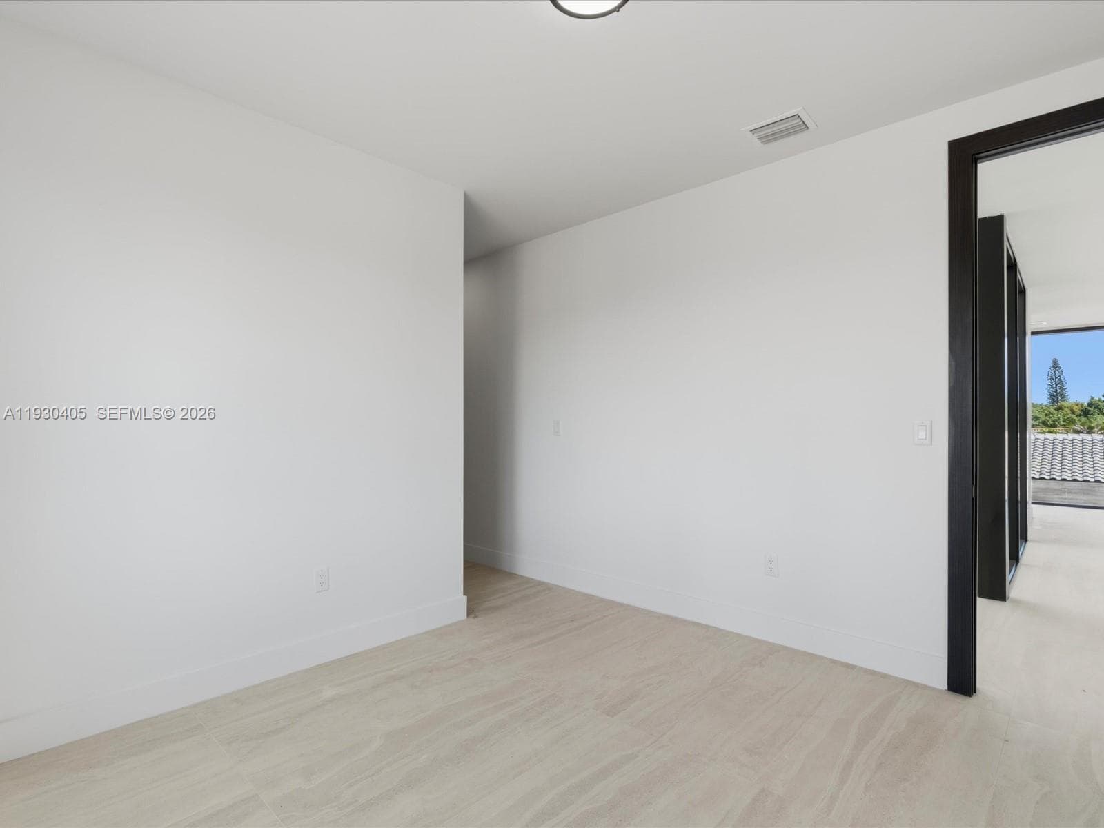 Interior space featuring neutral wall paint, wood-finish flooring, and dark-toned door trim
