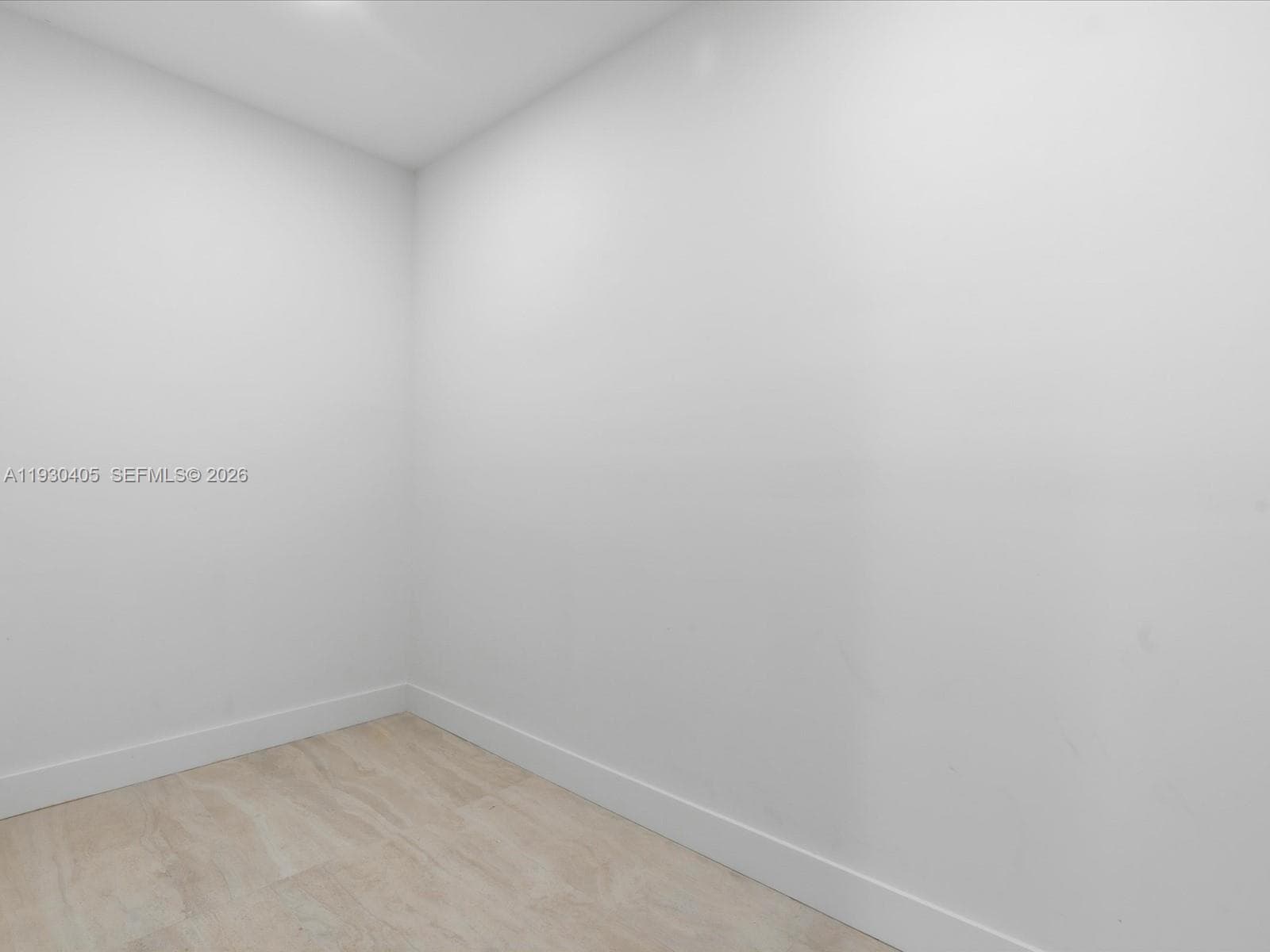 Neutral-toned interior space featuring smooth white walls and wood-finish flooring