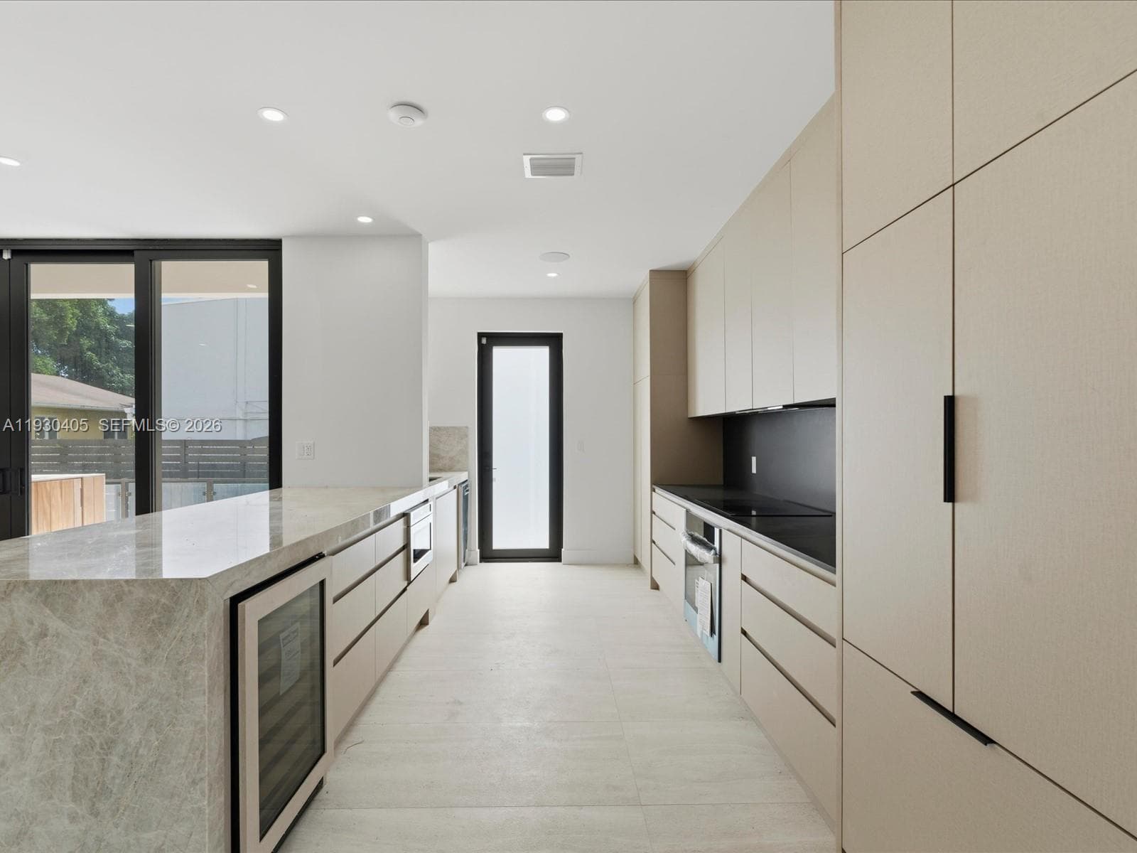 Kitchen featuring flat-panel cabinetry, stone countertops, a built-in wine refrigerator, integrated oven, and tile flooring