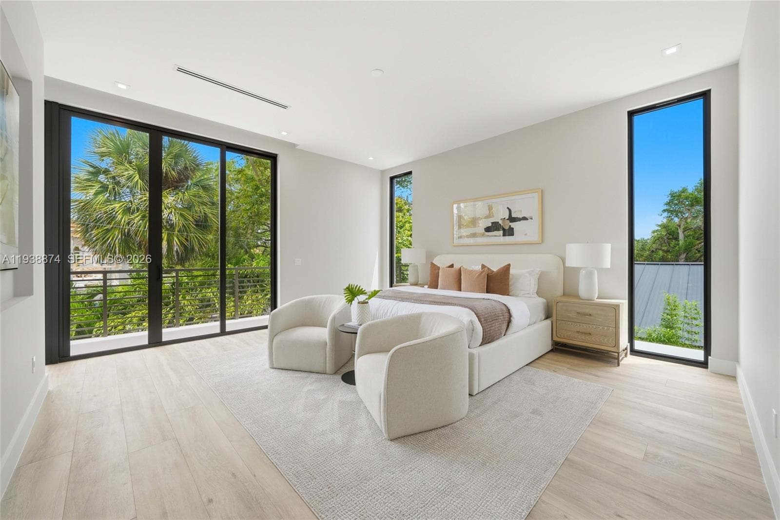 Spacious interior featuring light wood-finish flooring, floor-to-ceiling windows, sliding glass doors, recessed lighting, and a private balcony