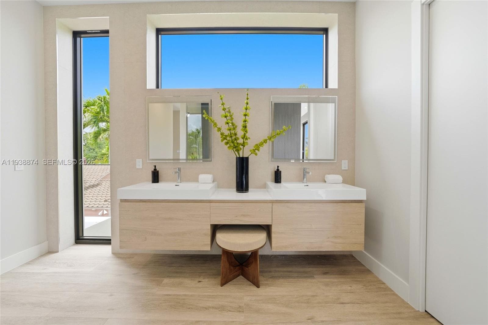 Modern floating vanity with dual rectangular vessel sinks, light wood-finish cabinetry, crisp stone countertops, and two wall-mounted rectangular mirrors, complemented by large windows providing ample natural light