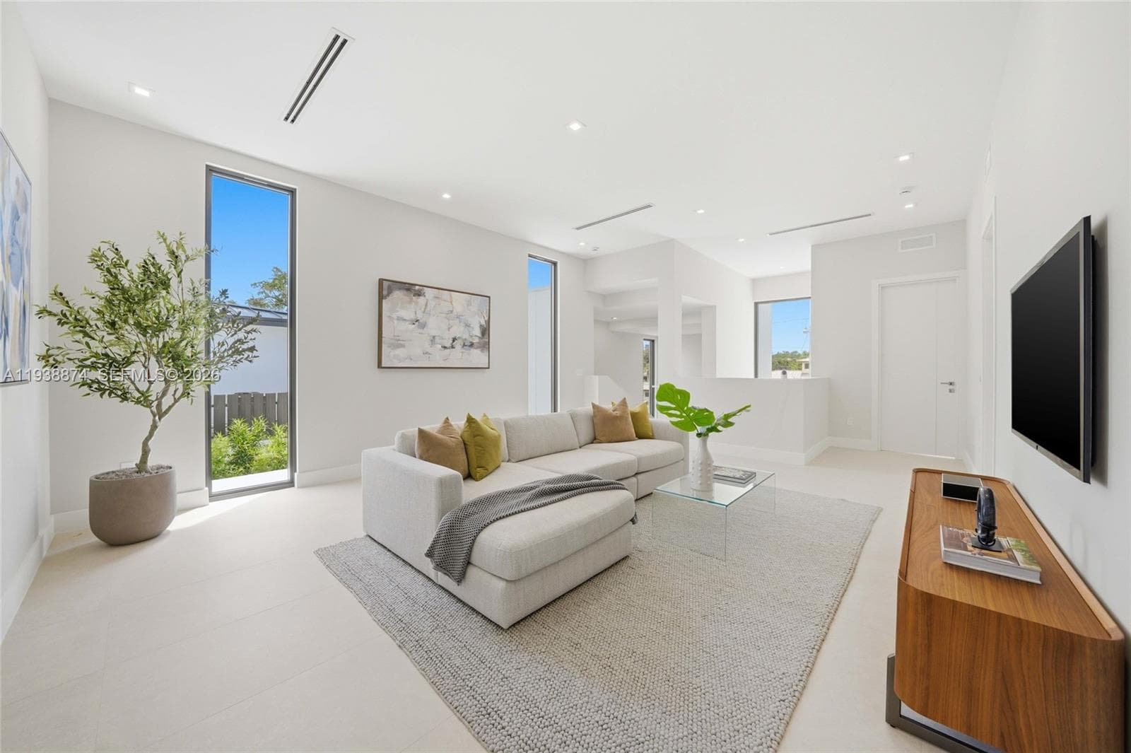 featuring high ceilings, large floor-to-ceiling windows, light-toned tile flooring, and recessed lighting