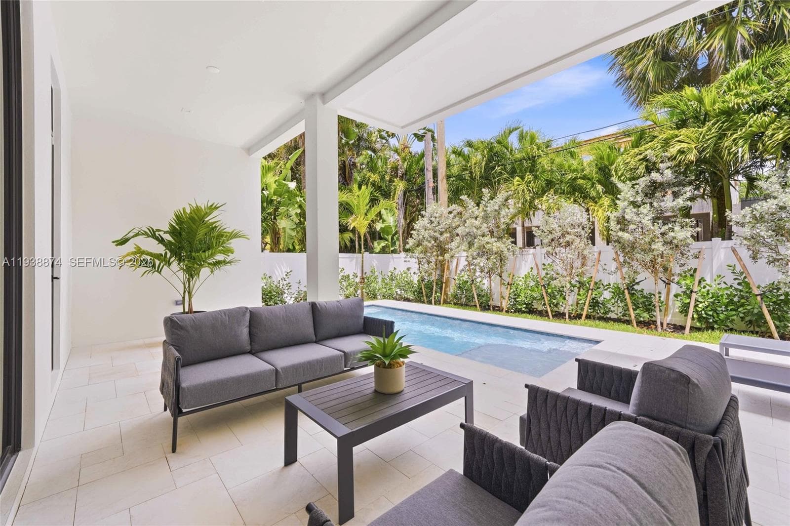 Covered patio featuring large-format stone-style tile flooring, recessed ceiling lighting, and a rectangular in-ground pool surrounded by privacy fencing and mature landscaping