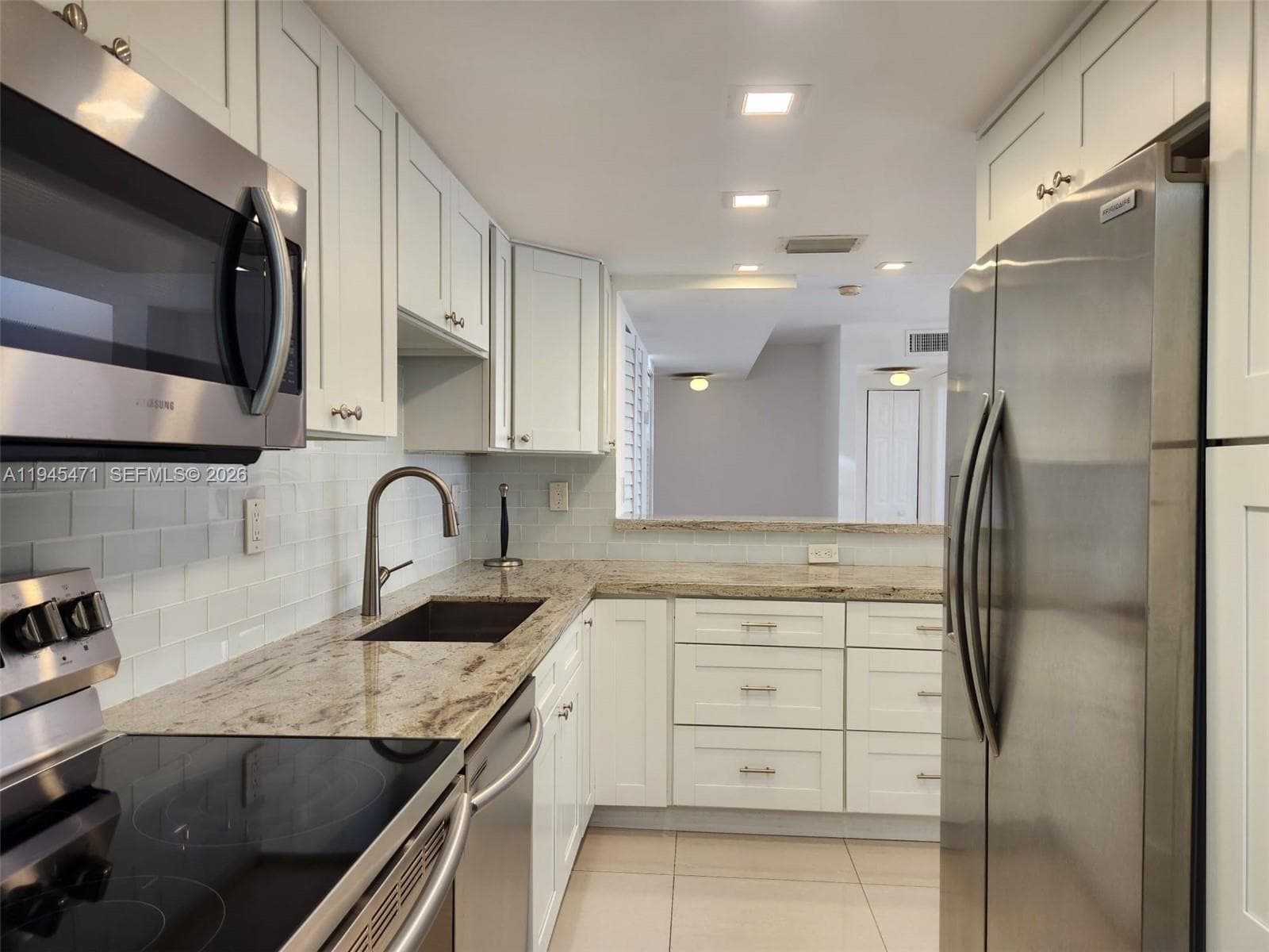 Bright and White kitchen with Stainless Steel appliances.