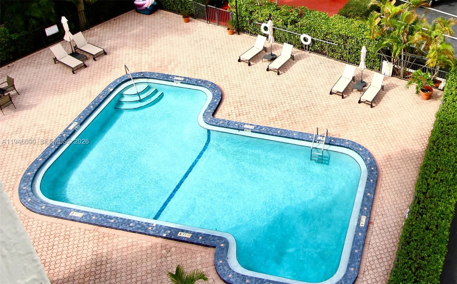 Building amenities feature a large pool area with lounge chairs, tables, and umbrellas.