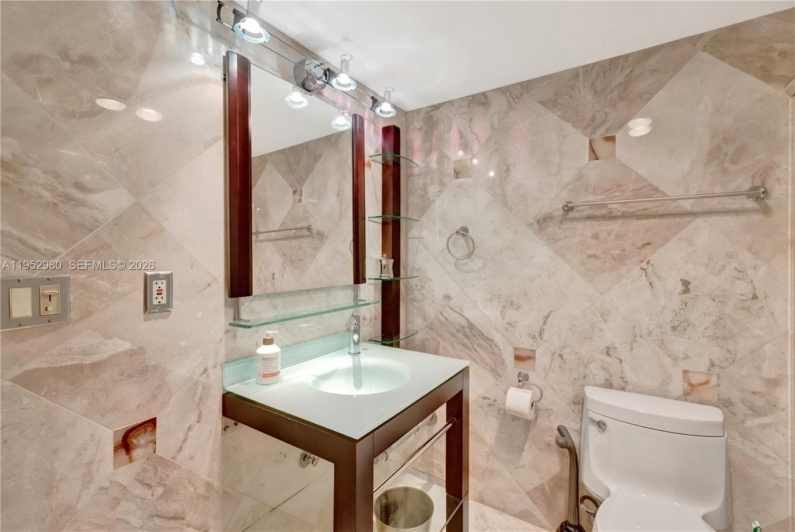 Marble walled bathroom with modern glass vanities