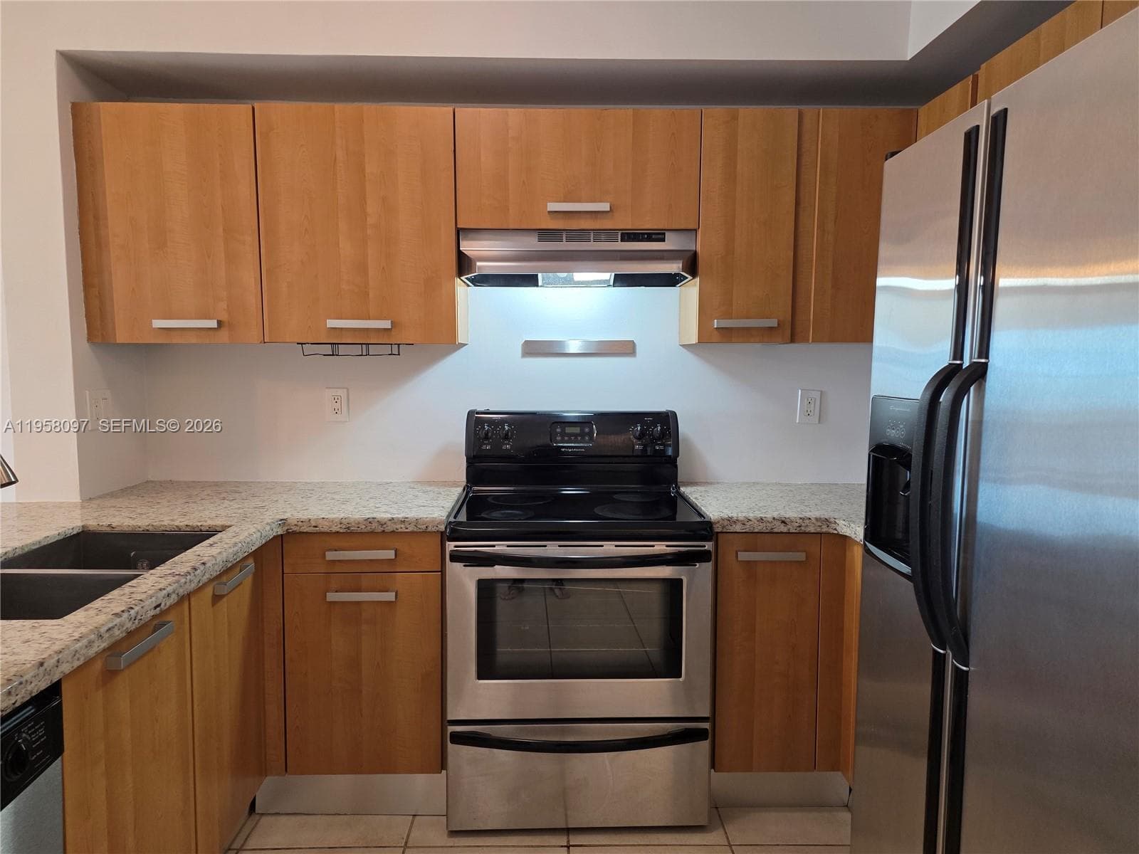 Well-equipped kitchen with stainless steel refrigerator, electric range, built-in microwave hood, and dishwasher.