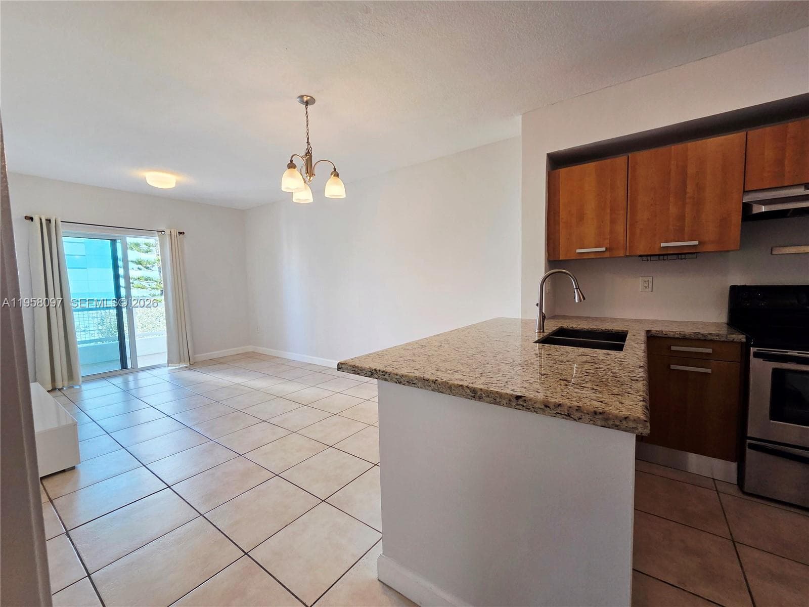 Open kitchen with granite countertops and stainless steel appliances flowing into the main living area and private balcony beyond.