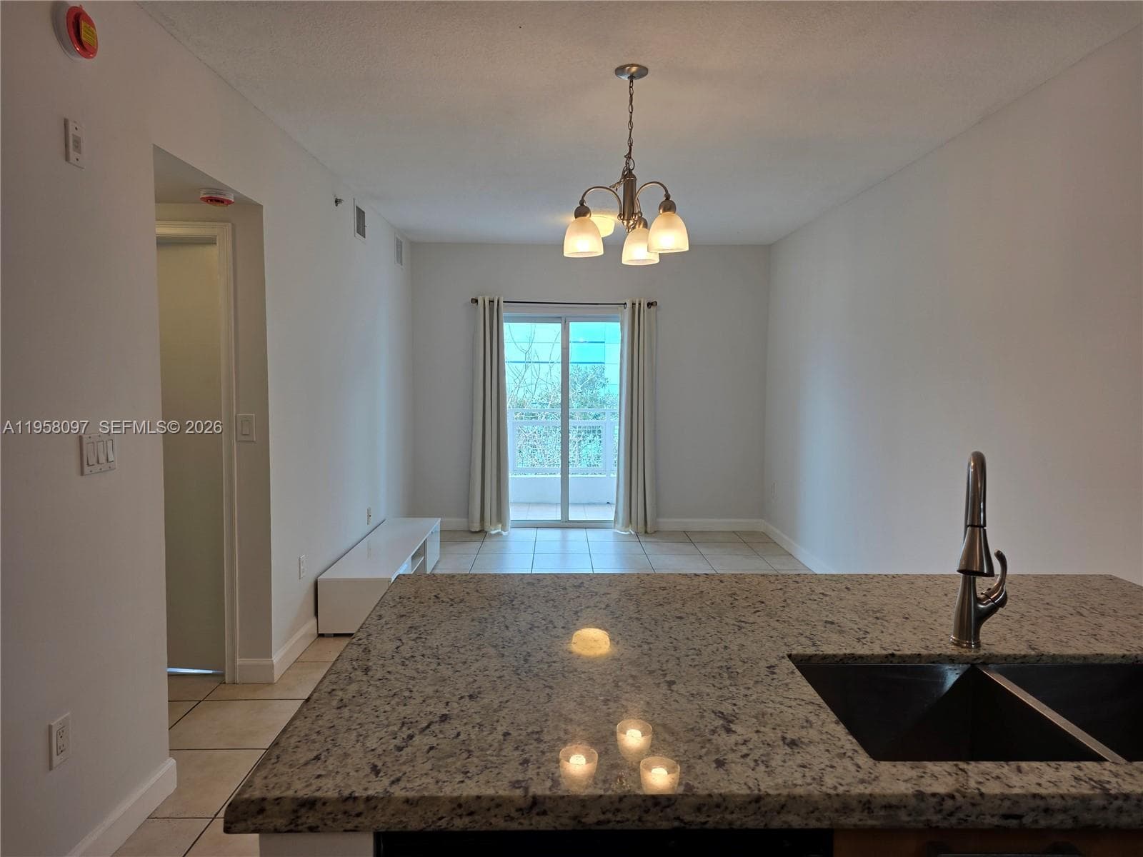 Spacious living area filled with natural light, featuring sliding glass doors that open to a private balcony, creating seamless indoor-outdoor flow.