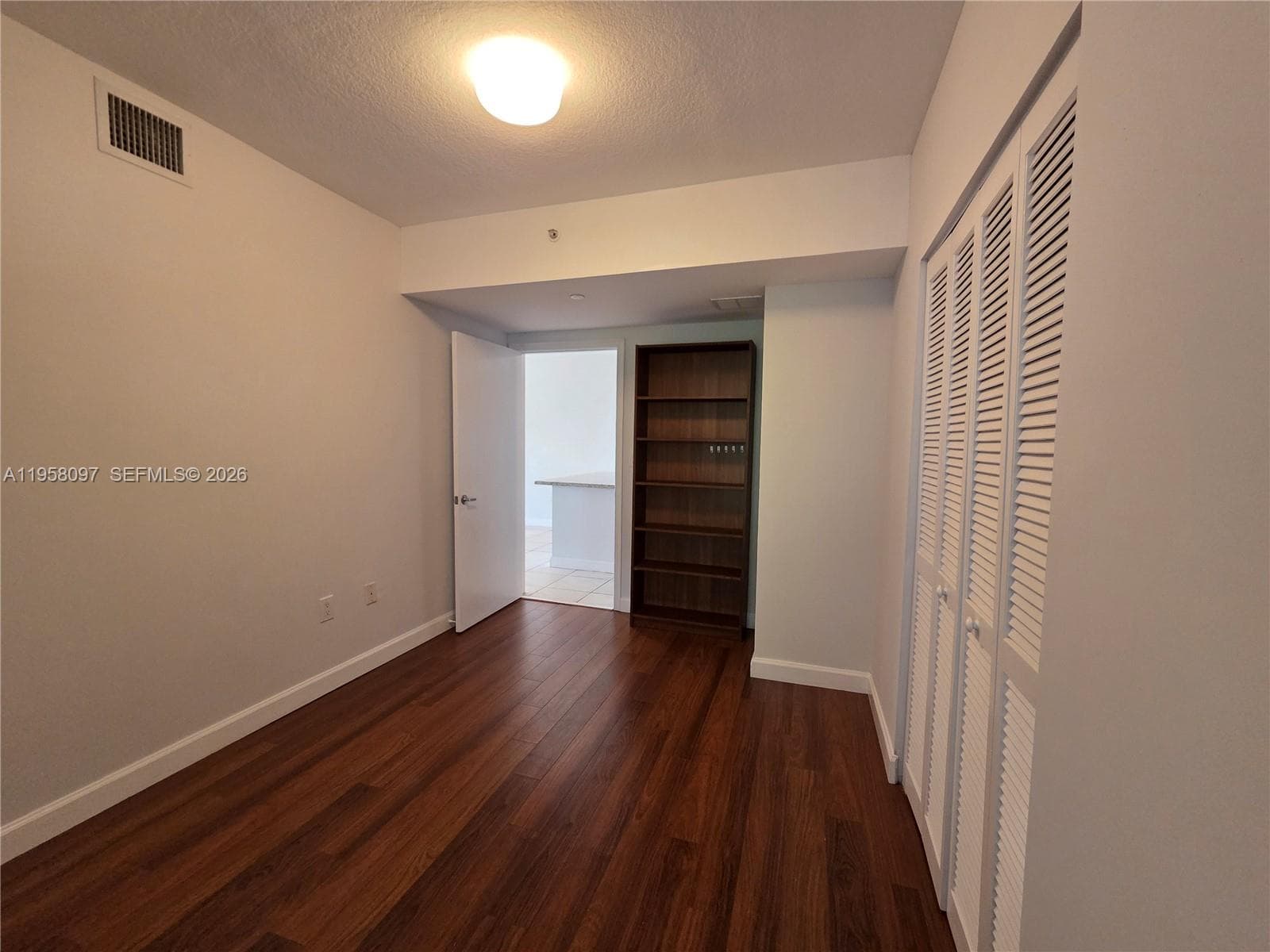 Bright bedroom with wood flooring and direct connection to main living areas, offering flexibility for guest room or home office use.