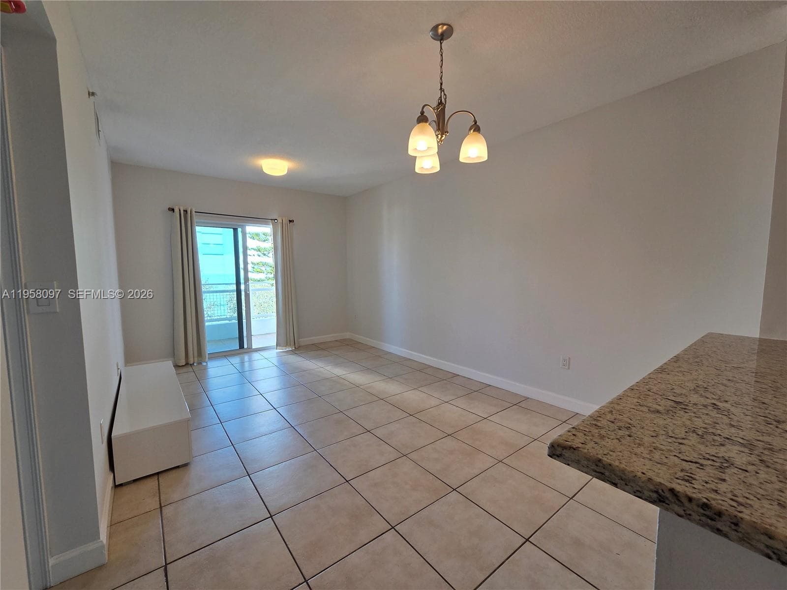 Bright open-concept living and dining area with neutral finishes, tile flooring, and direct access to a private balcony. Functional layout ideal for entertaining or everyday living.