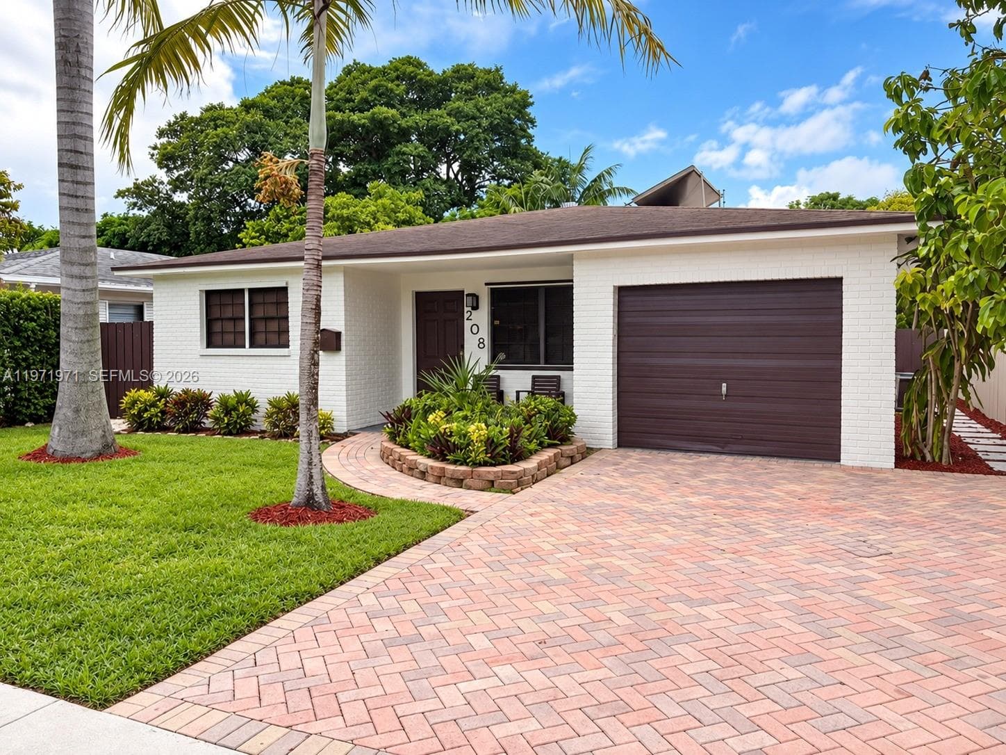 Single-story residence featuring a painted brick exterior, an attached one-car garage with a horizontal-panel door, and a herringbone-patterned paved driveway