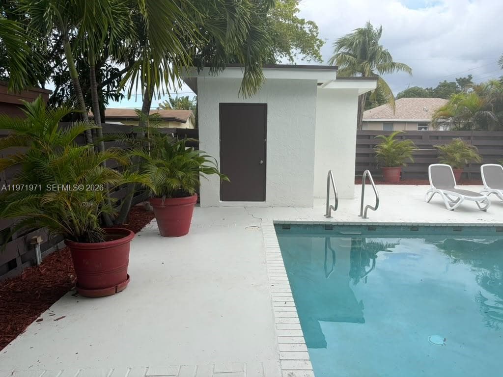 Swimming pool with tiled coping, exterior pool house, and horizontal privacy fencing