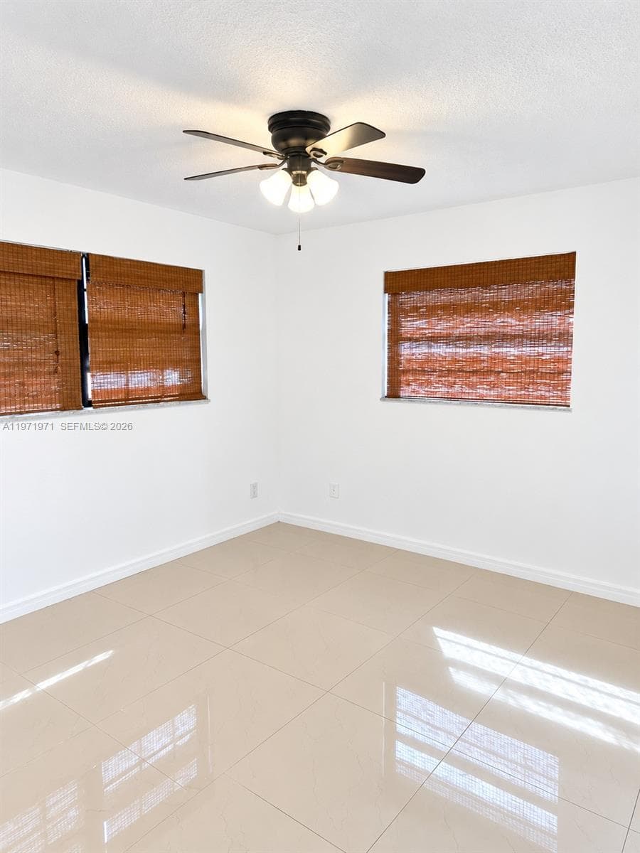 Room featuring large-format tile flooring, neutral wall finishes, and a central ceiling fan with integrated lighting