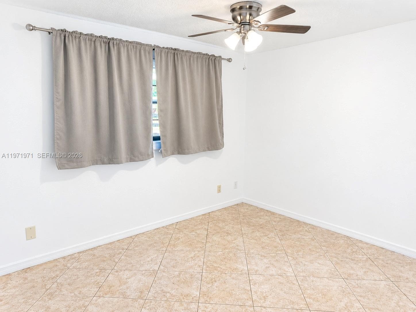 Neutral-toned tile flooring, white wall finishes, and a brushed nickel ceiling fan with integrated lighting
