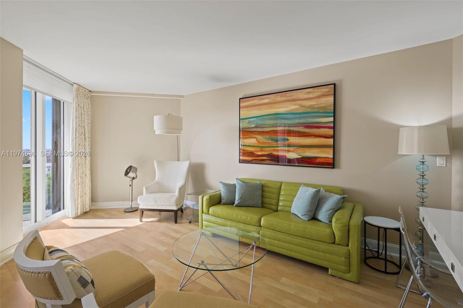 Sunlit primary suite lounge with floor-to-ceiling glass & balcony access