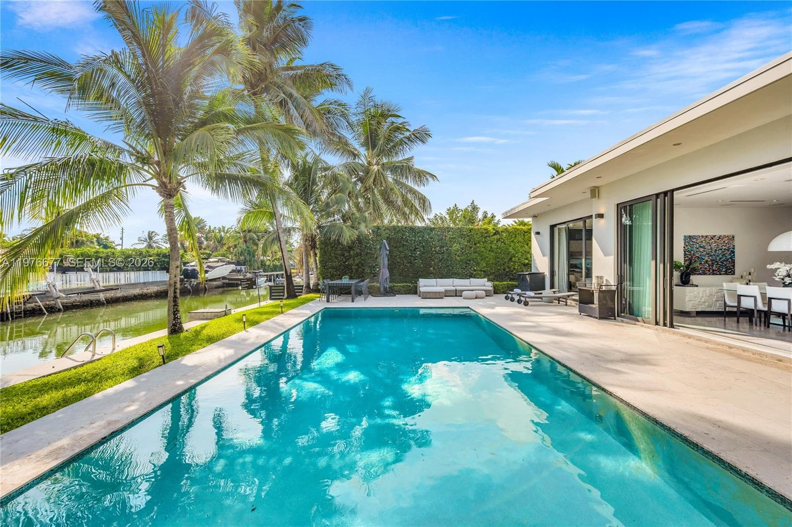 In-ground swimming pool with stone-surround.  patio, waterfront bulkhead, and privacy-hedged perimeter. Oversize pool