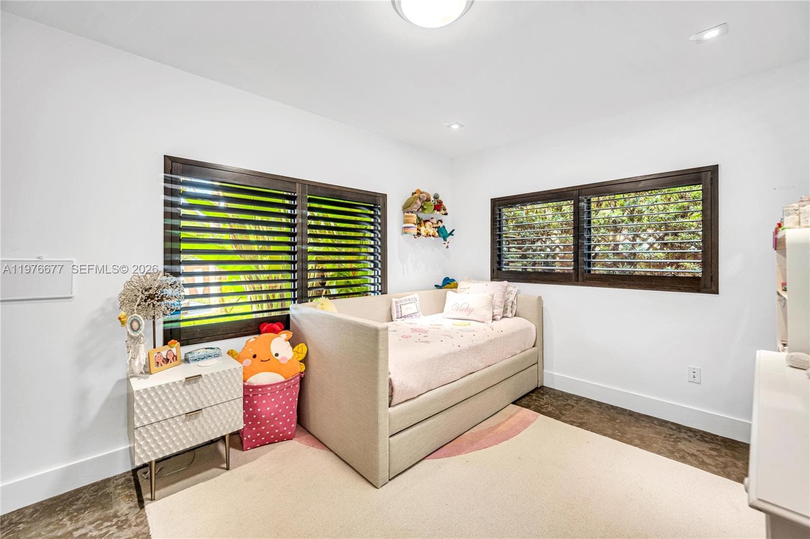 Room featuring dark wood-finish flooring, white walls, recessed ceiling lighting, and large windows with dark wood shutters