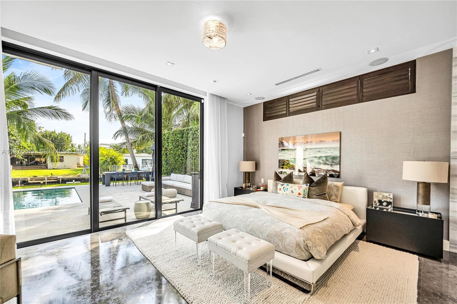 Floor-to-ceiling sliding glass walls, polished stone flooring, custom wood-slat transom cabinetry, recessed ceiling lighting, and expansive exterior patio access