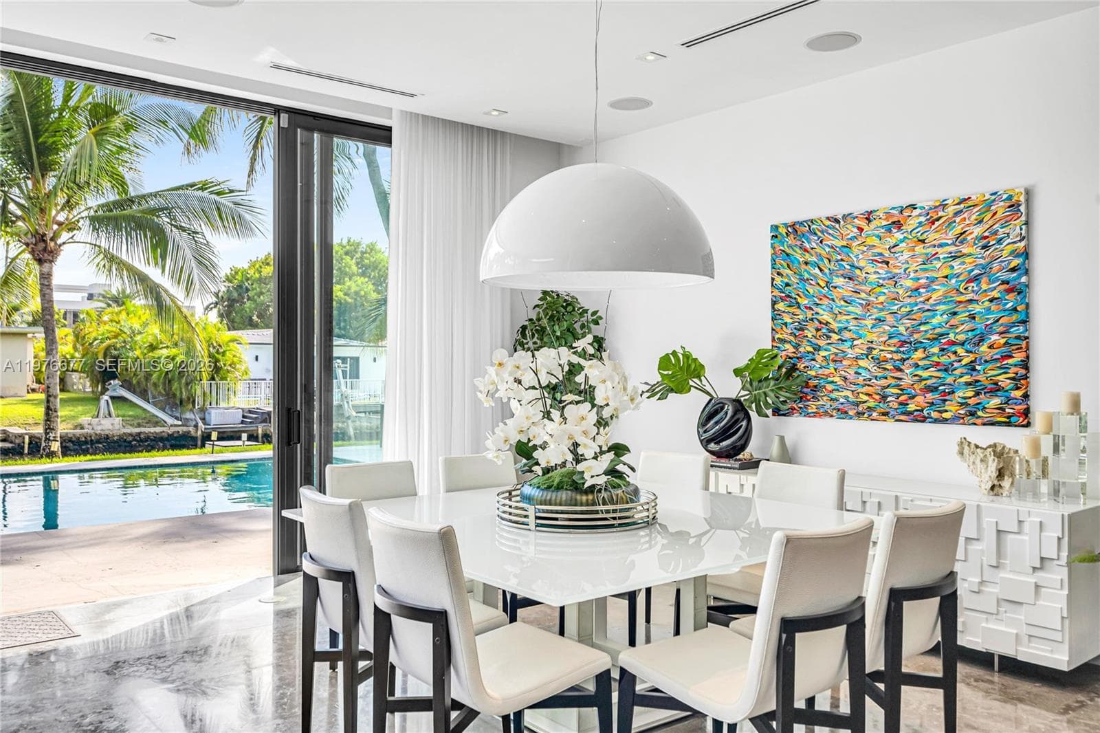 Floor-to-ceiling sliding glass doors, large-format polished flooring, recessed ceiling lighting, and a prominent dome pendant fixture