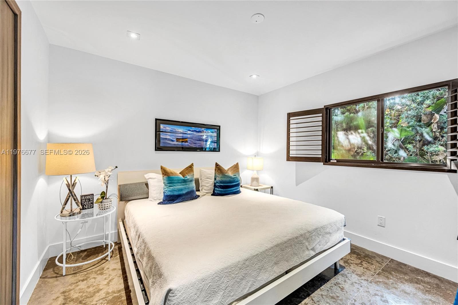 Neutral-toned tile flooring, recessed ceiling lighting, and horizontal window shutters featuring exterior greenery
